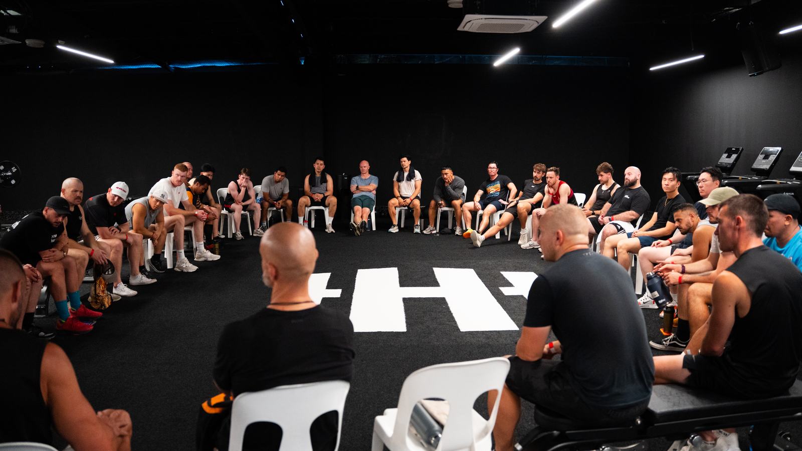 Men circled up sharing openly at a Gym Church session